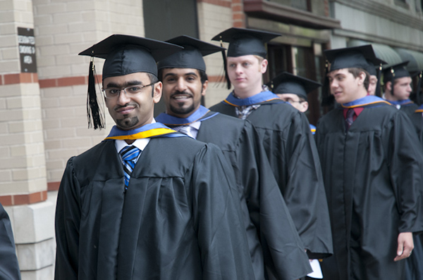 Graduates smile as they wait in front of the Community Arts Center.
