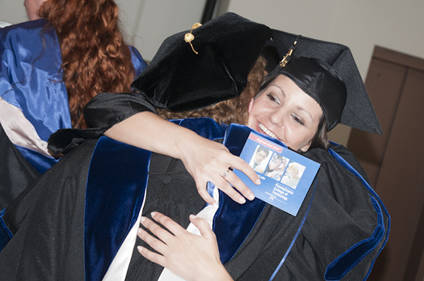 Director of Nursing Sharon G. Auker (face hidden) offers a congratulatory hug to a nursing grad.