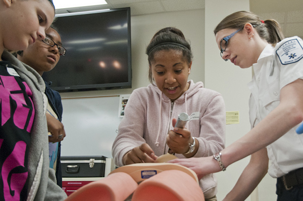 Emergency medical services student Debra L. Mott helps a Curtin Middle School student to “intubate” – insert a breathing tube into – a manikin. 