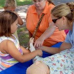Jessica L. Bower (right) helps a young visitor bandage a child manikin, which she also used to show boys and girls how to feel their pulse.