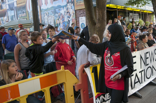 Surgical technology student Hanan Almuhathab gives out coloring books in a densely crowded downtown.