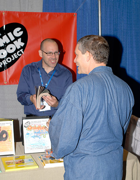Presenter Joseph E. LeBlanc stops by keynoter Michael Bitz's Comic Book Project booth in the Field House.