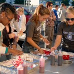 Employing squirt bottles – a change over past years' method of dunking garments into buckets of pink – participants douse their T-shirts with color. Employing squirt bottles – a change over past years' method of dunking garments into buckets of pink – participants douse their T-shirts with color.