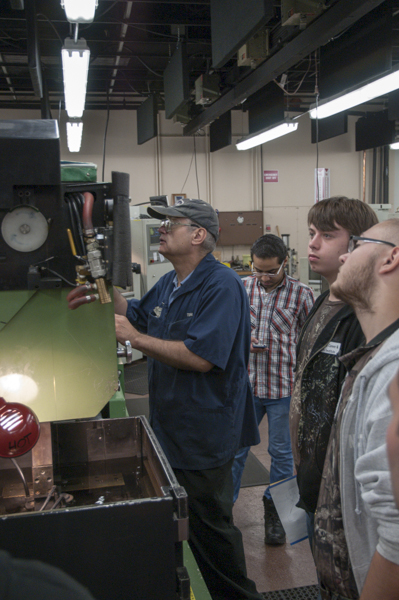 With Tom Livingstone, associate professor of machine tool technology/automated manufacturing, a group watches the process of electrical discharge manufacturing in the Machining Technologies Center.