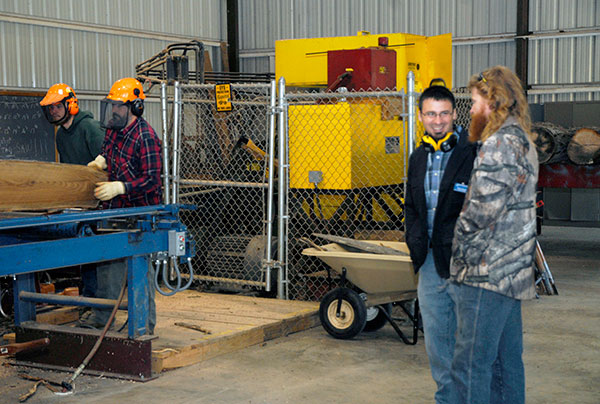As students log some instructional time in the working sawmill, Erich R. Doebler, lab assistant for forest technology, talks with an Open House visitor.