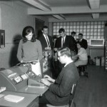 Members of the second graduating class of data-processing students practice on the college’s first computer, an IBM 1620 (mainly hidden in the background), in the college’s first computer lab, in Unit 6, in 1967.