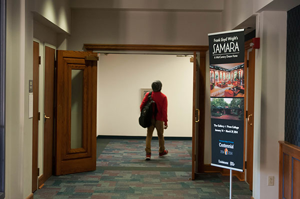 A student walks past a sign promoting Thursday's lecture and the gallery exhibit.