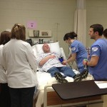 A simulated angina patient, stricken in the dental hygiene clinic, talks with physician assistant and nursing students after transport to the ER.