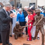 Penn College President Davie Jane Gilmour, chair of the Little League International Board of Directors, stands at "home base" for the group that sponsored the catcher statue, joined by Lycoming College President Kent C. Trachte (left foreground); state Sen. Gene Yaw (to Gilmour's left), chairman of the Penn College Board of Directors, who unveiled the sculpture; and Williamsport All-Star Little Leaguers. A plaque denoting the colleges' sponsorship adorns the backstop.
