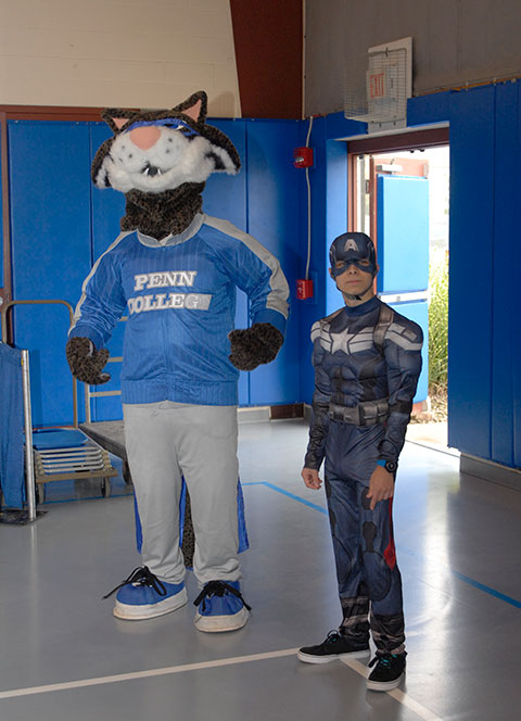 The mascot for whom the event is named (portrayed Saturday by Dakotah J. Hewston, a renewable energy technologies major from Dingman's Ferry) is escorted through the Hall of Merchants by superhero Caleb J. Maenza, of Sayre, a pre-occupational therapy assistant student.