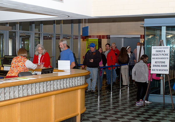 Student Activities' Mary Jane Baier greets registrants at the Bush Campus Center information center, adding a welcome burst of friendly to the day's drizzly start.
