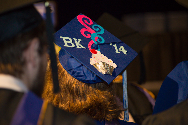 A commencement cupcake tantalizes from atop a baking and pastry arts grad's cap.