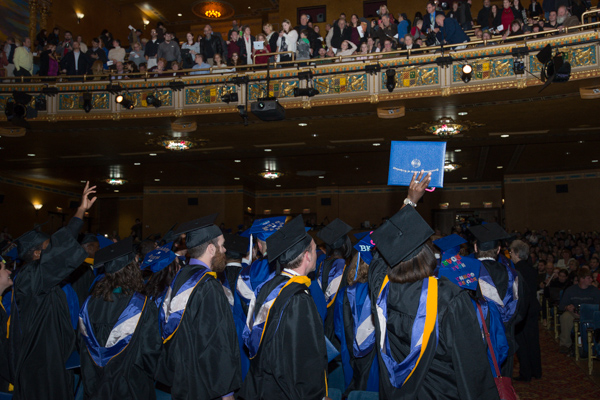 With arms and diplomas raised toward the balcony, graduates prepare to recess.