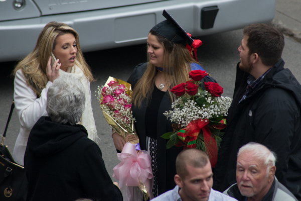 Her arms filled with floral tributes, a new alumna makes memories (as well as plans for the day ahead).