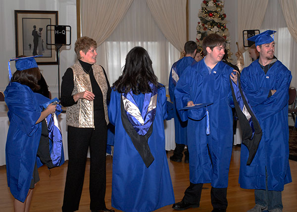 A line of students forms around Kay E. Dunkleberger, among the college employees on hand to help with pre-commencement wardrobe assistance.