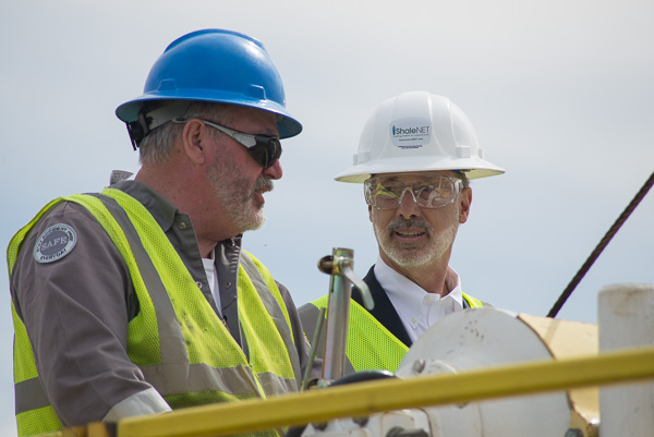 The governor dons a hard hat to join Moore on the drilling rig.