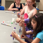 Sand artists intently layer colors ...
