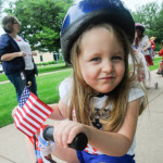 A child makes friends with the camera as she rides by.