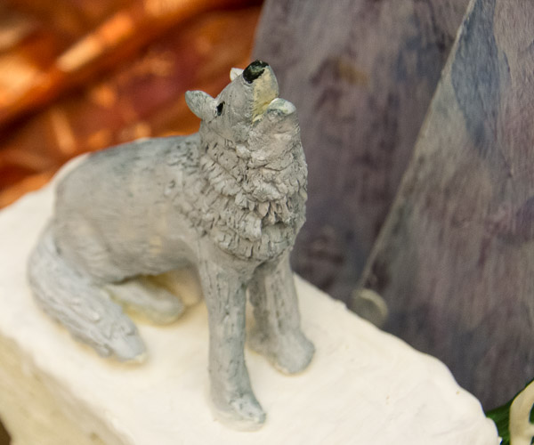 Tielmann’s chocolate wolf howls before a landscape of purple mountains.