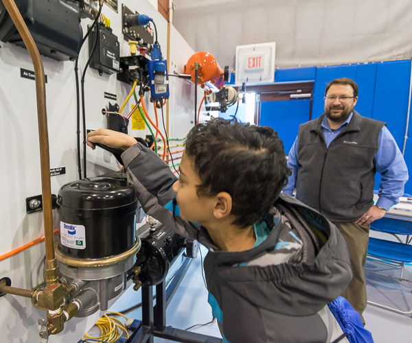 Justin W. Beishline, assistant dean of transportation and natural resources technologies, supervises a youngster's operation and understanding of a truck-brake simulator.