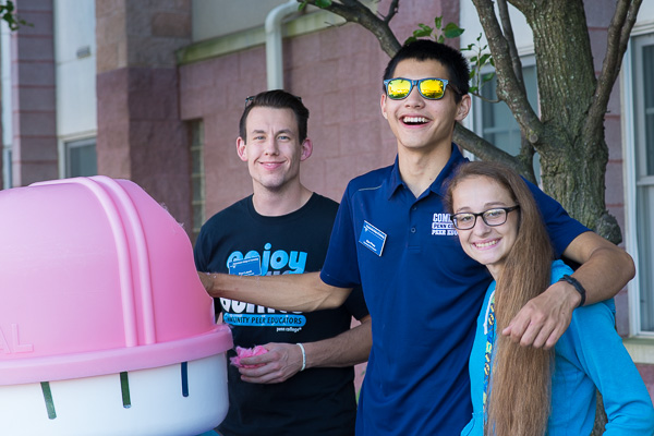 Community Peer Educators Paul M. Lasell (left) and Samuel J. Pham hang out at the cotton candy machine with “customer” Audrey M. Bowser, a freshman in building science and sustainable design: architectural technology concentration, from Tyrone.