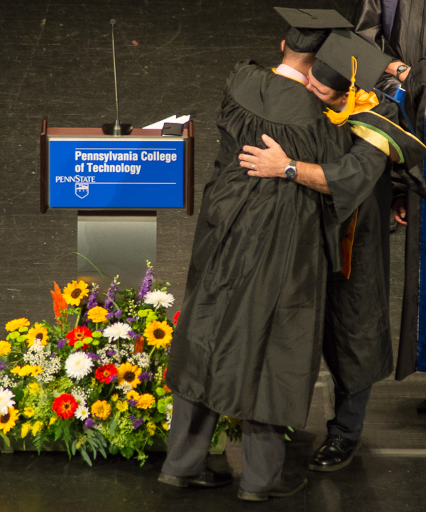 Cody L. Breon, physician assistant graduate (with his back to the camera), receives a hug from his father, Brady L., assistant professor in the paramedic program.