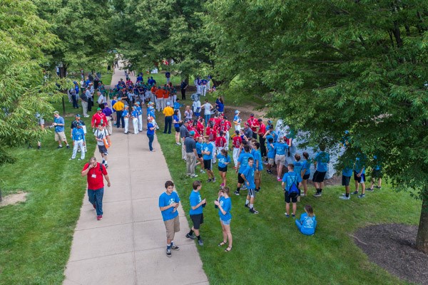 Teams spread out on the lush, late-summer green of a well-maintained campus.
