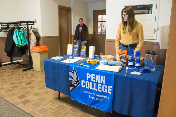 Community Peer Educator Nina L. Walk staffs an information table near the gym entrance.