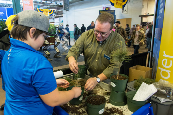 Carl J. Bower Jr., assistant professor of horticulture, helps a child to plant a white pine tree. The child’s father said they have the perfect spot: outside the cabin the two have been fixing up.