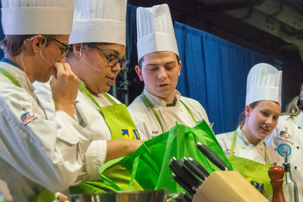 Students (from left) – Parobek, Smith, Herceg and Callahan – dig into their mystery market basket to learn the required ingredients.