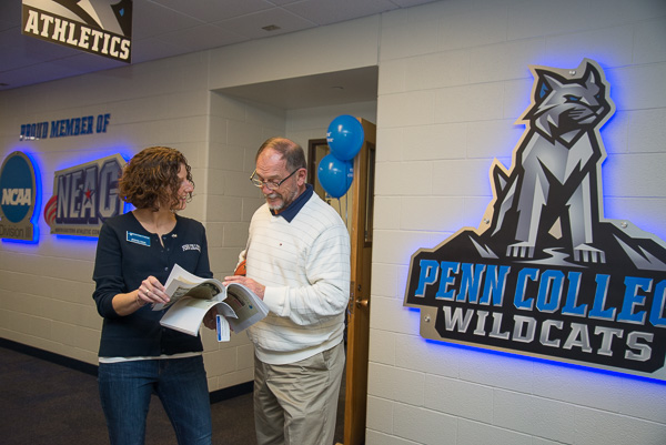 Alumni Relations Director Kimberly R. Cassel shows Collins copies of WACC’s Spotlight campus newspaper featuring his basketball achievements and other campus involvement …
