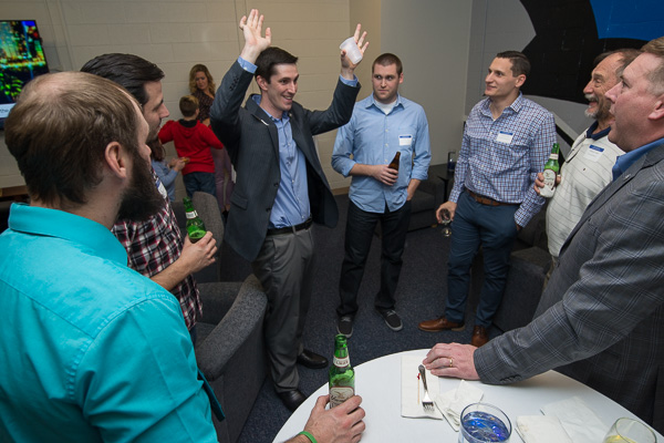 As reunion guests huddle around, Wildcat men's basketball coach Ryan Callahan entertains them with “tall” tales.
