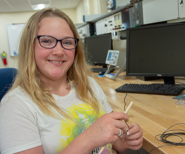 In the Electrical Trades Center, a student from Milton Area Middle School begins wrapping wire around a pencil to complete experiments with electromagnetism.