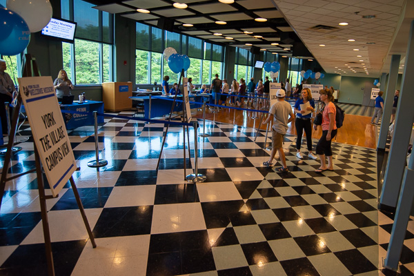 This year, residence hall check-in activities moved to the visually appealing Penn’s Inn, in the Bush Campus Center. Heather M. Shuey (at right, holding white papers), director of development and compliance, steers a family in the right direction.