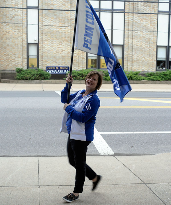 Noelle B. Bloom, assistant director of dining services, greets early risers with a friendly wave of the flag.