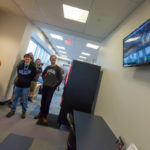 Waiting in line, students clearly enjoy watching the room’s action on a monitor.