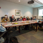 Grimsley (standing) reads a healing poem as participants experiment with stitching while wearing blindfolds.