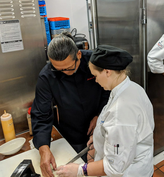 Morimoto guides Penn College student Autumn L. Schabener in making his shrimp tempura rolls.