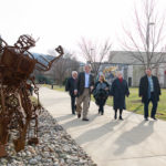 The entourage passes the Student Bodies art installation that lines the campus mall ...