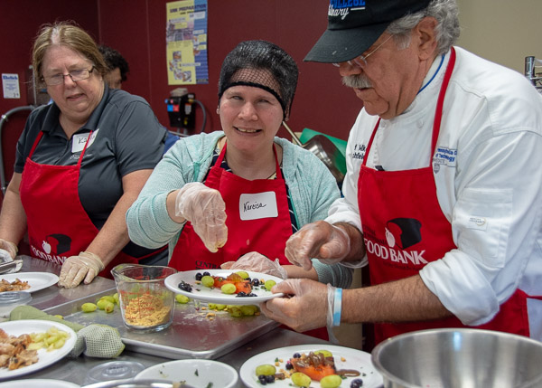 Teammate Narcisa Ebner (center) adds the finishing touch to the blue team’s dessert. At left is team member Karla Sexton, of River Valley Health and Dental.