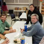 General Services' Josh J. Wrench (in green shirt), associate director of project management, and Jamie L. Plocinski (standing), facilities service assistant, make friends at mealtime.