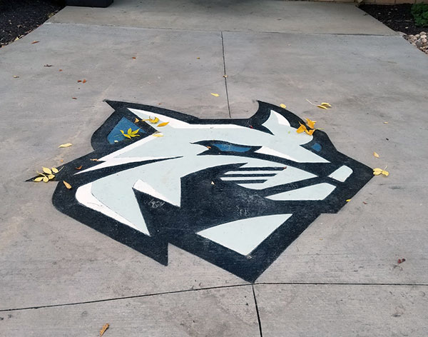 Fallen leaves dance across the formidable face of the Wildcat, concrete students' recent enhancement of the Field House entrance.