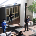 Using square-foot floor tiles to maintain the space between them, students from the college's School of Engineering Technologies listen to Potts' on-the-job memories from construction of their immediate surroundings.
