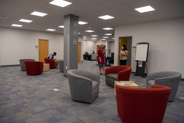 Director Christie Bing Kracker (in red) chats with Margaret D. McCracken, human resources specialist, during an open house. A student (left) is waiting for an appointment with his LEAP adviser.