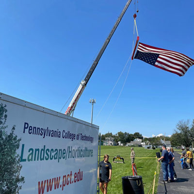 A stiff breeze catches "Old Glory," flying vertically from a crane near a trailer from the Schneebeli Earth Science Center. Under faculty supervision, youngsters climbed aboard heavy construction equipment for a hands-on (and eye-opening) taste of a Penn College education.