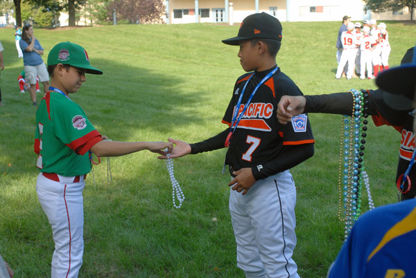 A Mexico player accepts a string of beads from a member of the Asia-Pacific team, representing Kaohsiung, Chinese Taipei.
