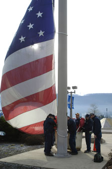 Penn College General Services workers begin to raise the American flag after repairs were made to the pulley system.