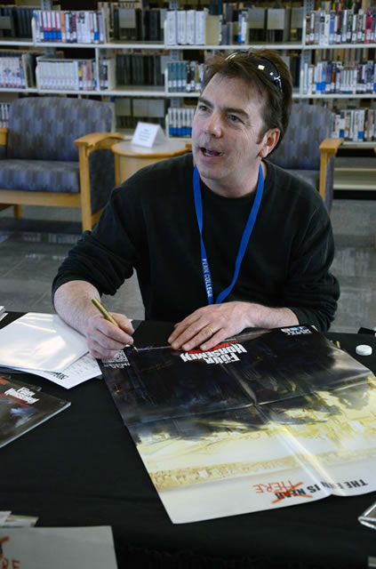 Michael Mendheim signs a poster shortly after his Friday presentation, "Next Generation: The Ins and Outs of the Videogame Industry."