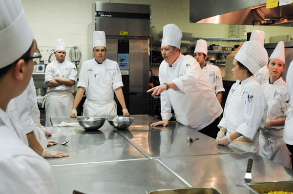 Chef Endy offers direction to the kitchen staff as they prepare to begin plating the second course.
