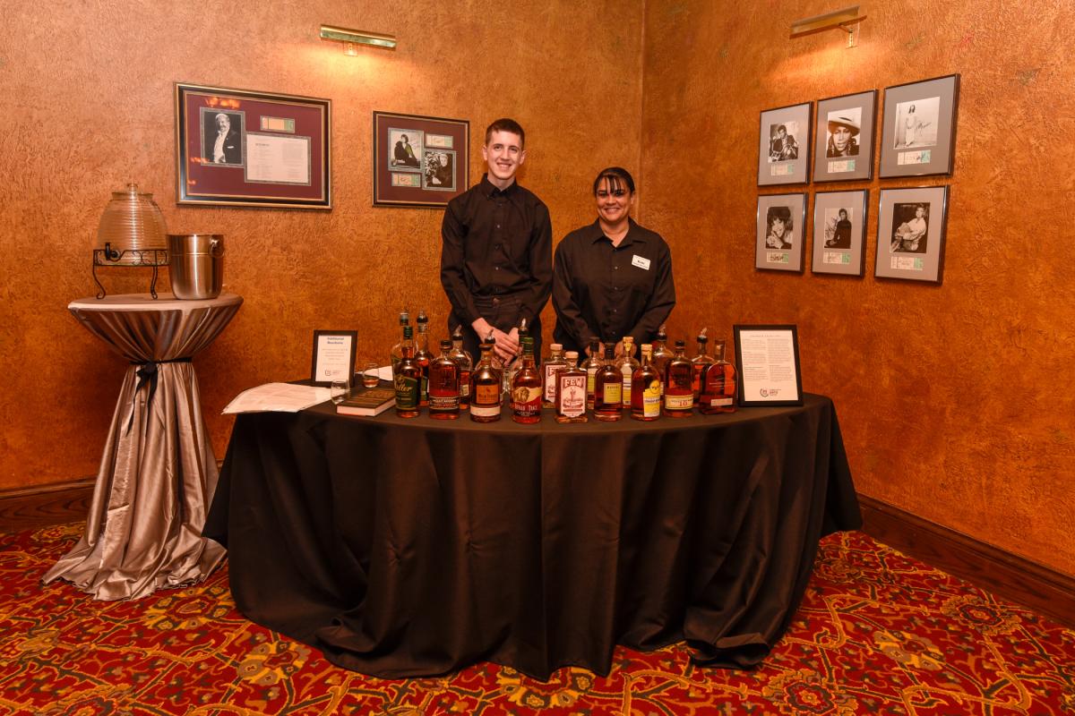 In a corner of the mezzanine, bourbon tastings are presented by Caleb J. Stemler (left), Le Jeune Chef waitstaff, and Kimberly A. Bressler, CAC bartender/concessionaire. Stemler is an applied management student who holds a degree in baking & pastry arts.